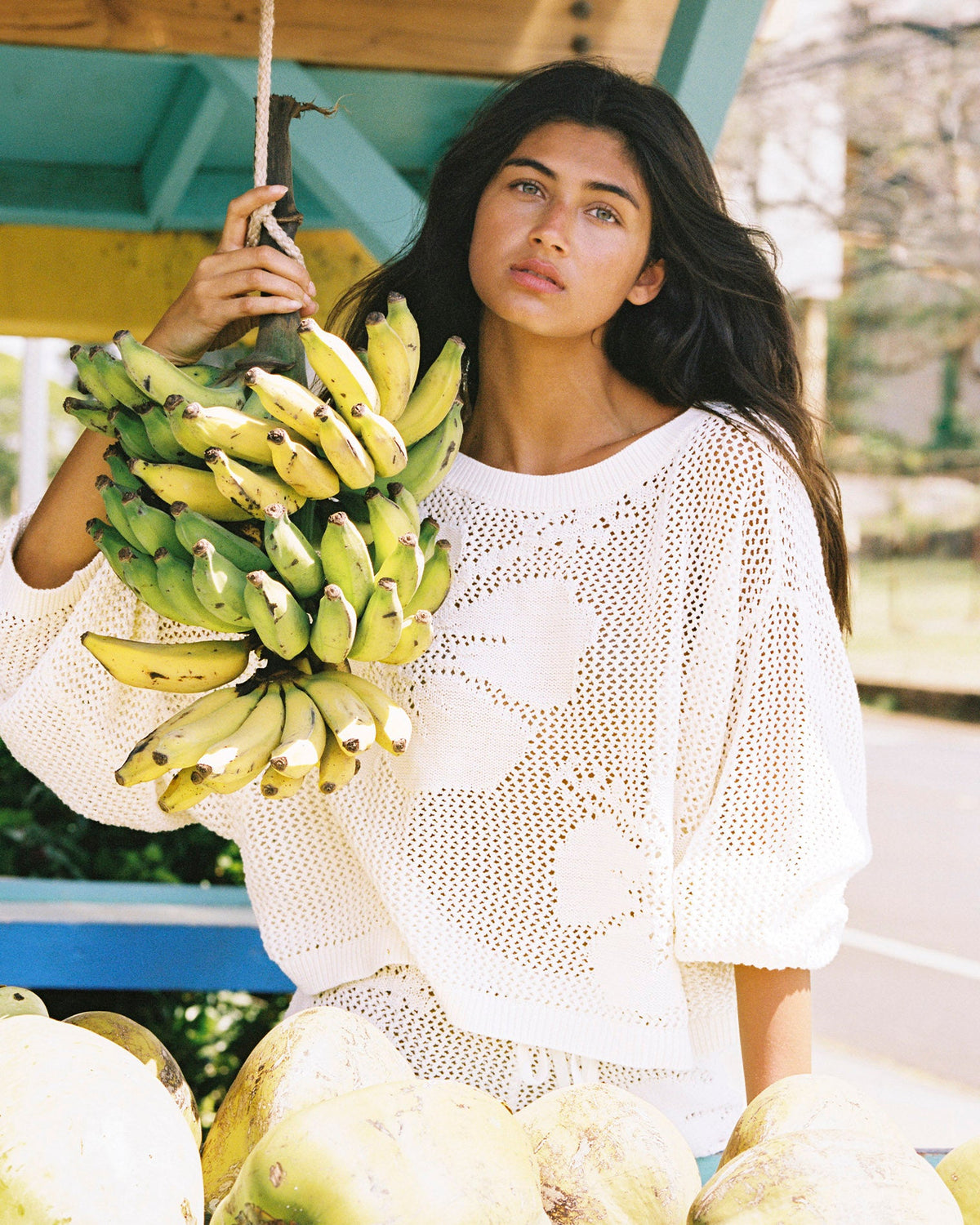 Cream | Badge:New Arrival_#B2AC88_#ffffff'
Model wearing the Island Time Sweater and Short posing with a bunch of bananas.
